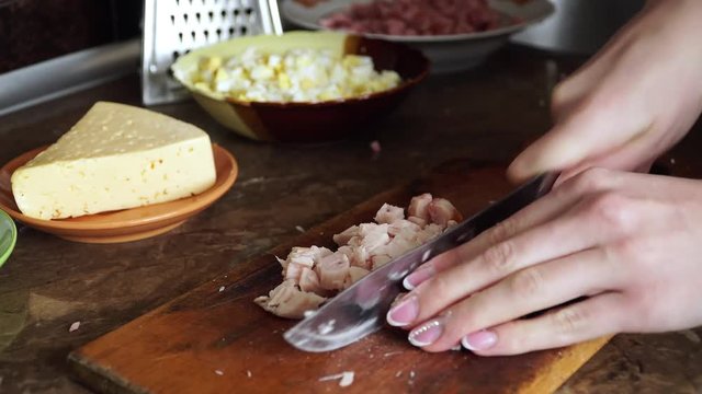 Housewife prepares dinner in kitchen and cuts meat with sharp knife
