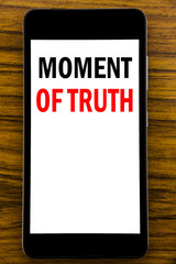 Handwriting Announcement text showing Moment Of Truth. Business concept for Hard Decision Pressure Written on mobile phone cellphone with wooden background with space on the table