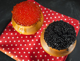 Red and black caviar in rustic clay pots chalk on a black background.