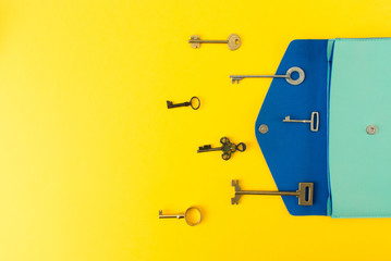 Flat lay of cute bag open out with a lot of old keys on colorful background with copy space, top view.
