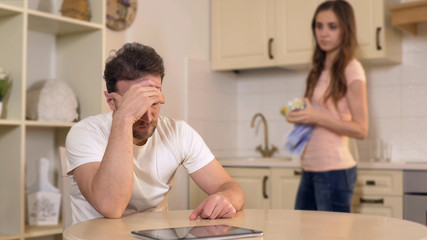 Obraz premium Wife scolding her unemployed husband at kitchen, chastising him for burning time
