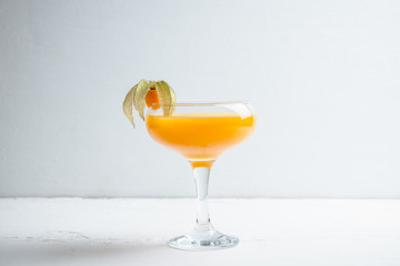 Sweet cocktail with peach liquor and physalis. Shallow depth of field. Selective focus.