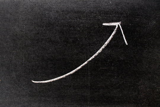 White chalk hand drawing in uptrend arrow shape on blackboard background