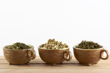 Three cups with green tea leaves on a white background