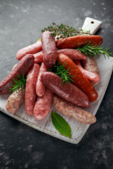 Freshly made raw breed butchers sausages mix in skins with herbs on white cutting board.