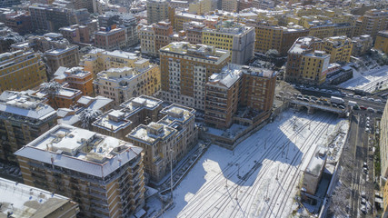 Aerial view of the Appia street in Rome, Italy. Around the tracks and roads there are the palaces and streets of the Italian city. The railroad tracks are made of steel. Everything is covered by snow