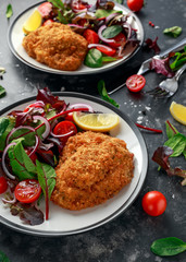 Breaded Chicken Kiev breast stuffed with butter, garlic and herbs served with vegetables in a plate.