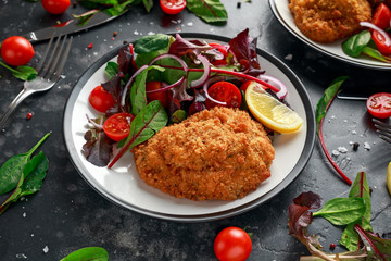 Breaded Chicken Kiev breast stuffed with butter, garlic and herbs served with vegetables in a plate.