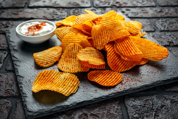Potato chips, snack crisps with red paprika and white dip sauce
