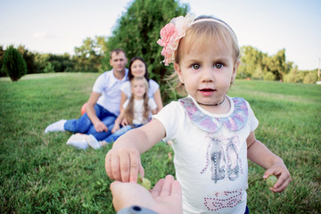 A little girl with big eyes takes the grapes from us