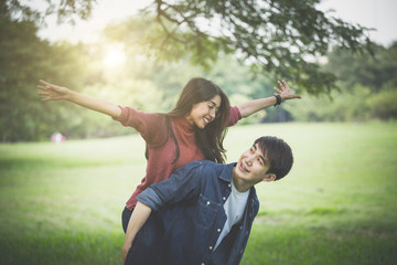 Couple of love, a man carry a girl on his back in park