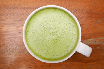 Top view of hot matcha green tea on wooden background