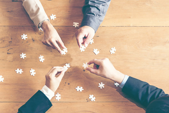 Businessman team work holding two jigsaw connecting couple puzzle piece for matching to goals target, success and start up new project in office, top view.  Business Concept.