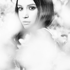 Beautiful young woman surrounded by flowers of apple-tree