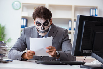 Businessmsn with scary face mask working in office