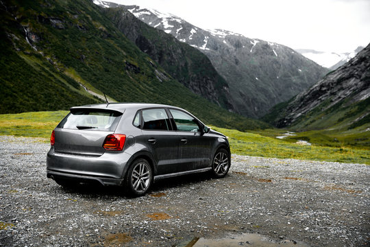 Grey modern car parking at a viewpoint in the mountains of Norway facing towards the green valley.