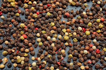 Mix of grind black pepper and black, white, red and yellow peppercorn. Selective focus.