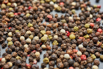 Mix of grind black pepper and black, white, red and yellow peppercorn. Selective focus.