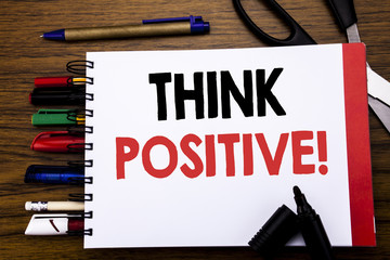 Handwritten text showing Think Positive. Business concept for Positivity Attitude Written on notebook, wooden background with office equipment like pens scissors colourful marker