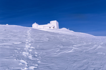 Amazing winter snowy mountain landscape. Scenic panoramic view of old astronomical observatory on the summit of mountain Pip Ivan on Chornogora mountain ridge in Ukraine. Outdoor activity background.