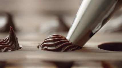 closeup of pastry bag filling candy mold form with chocolate cream. Side view macro