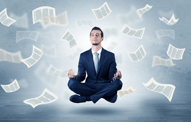 Businessman meditating with flying paper concept