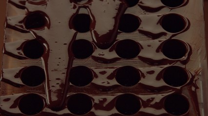 chocolate candy mold form in process of creating candys. liquid chocolate falling down from candy mold