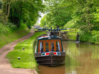 Moored narrowboat between two canal locks  on the Shropshire Union Canal near Audlem in Cheshire,...