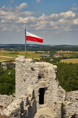 Polska flaga narodowa łopocząca na wieży obronnej zamku w Ogrodziencu, w tle piękny letni krajobraz okolicy