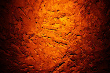 Natural texture created on the wall in the underground cave in Mazi underground city, Sehri, Turkey, enlightened by orange color spotlight