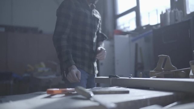Handsome man in his fourties working with wood in his workshop