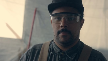 Obraz premium closeup portrait of mixed rase worker in his garage put up protecion glasses