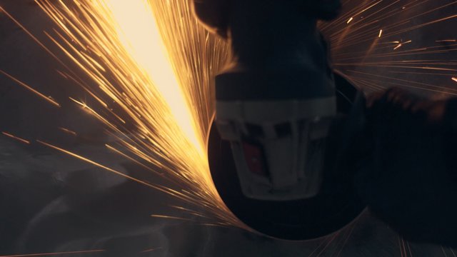 Worker using industrial grinder. Worker in garage makes work with metall and grinder. many bright flying sparks