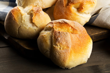 Bunch of whole, fresh baked wheat buns on dark wooden table