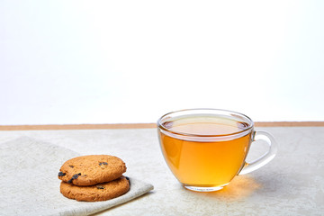 Shallow depth of field photo of a glass cup of black tea with brownies on a dark greyish marble background.