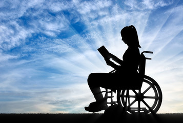 Fototapeta na wymiar Silhouette of a disabled woman in a wheelchair reading a book