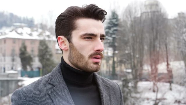 Handsome young stylish man walking in city by the river in snowy day. Turin, Italy