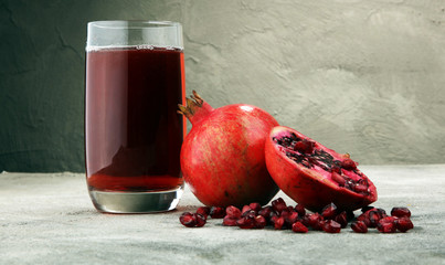 Glass of pomegranate juice and pomegranate fruit on old background