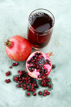 Glass of pomegranate juice and pomegranate fruit on old background