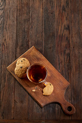 Fototapeta na wymiar Cup of tea with cookies on a cutting board on a wooden background, top view