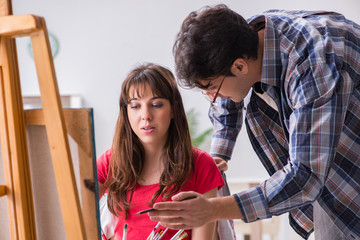 Artist coaching student in painting class in studio