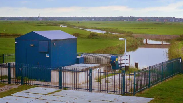 Dutch sea dike sluice gate polder drainage water outlet view towards main channel overcast