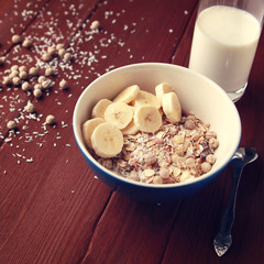 Healthy breakfast. Granola bowl with banana, raisins and nuts. And a glass of milk on the wooden background. Close up photo. Sweet vegan dish. Morning oatmeal closeup.