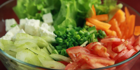 Glass bowl with cutted vegetables for a salad. Close up. Tomatoes, celery, bell pepper, leafy greens and cottage cheese cutted in pieces. Lacto vegetarian dish.