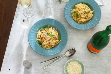 Dinner table. Two plate of pasta carbonara with glass of white wine on white wooden table, top view