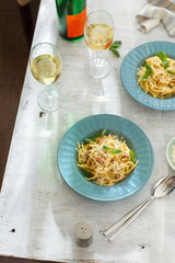 Dinner table concept. Top view two plate of pasta carbonara with glass of white wine on white wooden table