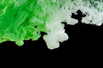 Mixing in water green and white paint isolated on a black background