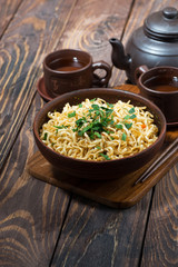 bowl with traditional Chinese noodles and green tea on wooden background, vertical