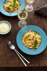 Homemade pasta carbonara with glass of white wine on wooden table, top view