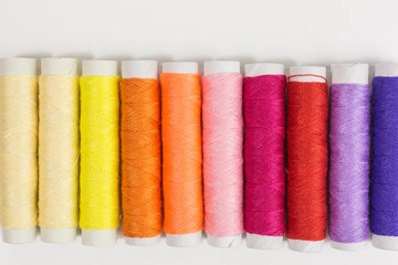 spools and bobbins of sewing thread in yellow, orange, pink, red and lilac